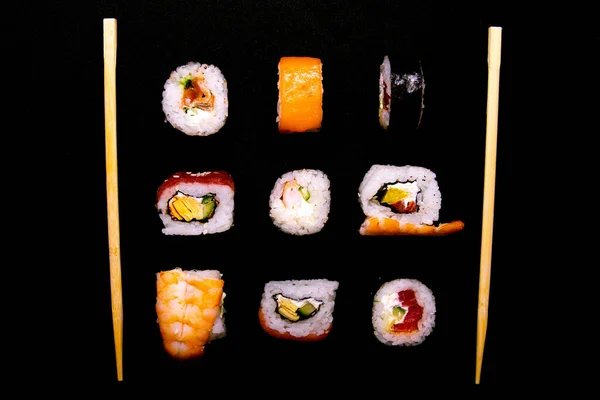 En uppsättning rullar av olika slag med sushi pinnar isolerade på en svart bakgrund — Stockfoto