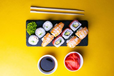 Suşi için granit tahta, suşi için çubuk, kırmızı marinaginger ve soya sosu yanında her çeşit rulo var..