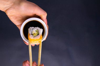 Sopalar Philadelphia rulosunu soya sosunun üzerine traş eder. Güzel bir kadının tabağındaki siyah bir arka planı uzatır.