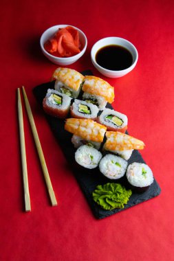 Suşi için granit tahta, suşi için çubuk, kırmızı marinaginger ve soya sosu yanında her çeşit rulo var..