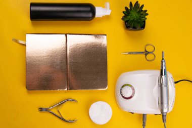 Set of cosmetic tools for manicure and pedicure on an orange background. Gel polishes, cutters, nail files, scissors and nippers. Top views.