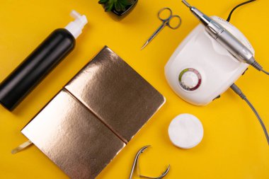Set of cosmetic tools for manicure and pedicure on an orange background. Gel polishes, cutters, nail files, scissors and nippers. Top views.