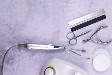 Set of cosmetic tools for manicure and pedicure on a concrete background. Gel polishes, milling cutter, nail files, scissors and tongs.