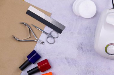 Set of cosmetic tools for manicure and pedicure on a concrete background. Gel polishes, milling cutter, nail files, scissors and tongs.