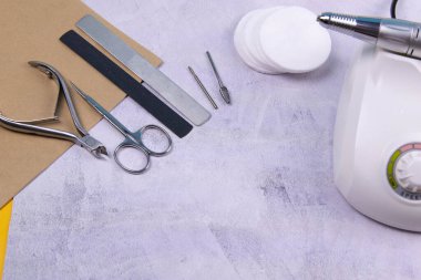 Set of cosmetic tools for manicure and pedicure on a concrete background. Gel polishes, milling cutter, nail files, scissors and tongs.