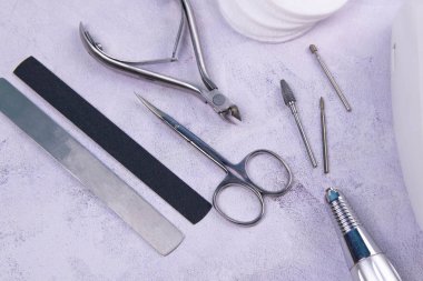 Set of cosmetic tools for manicure and pedicure on a concrete background. Gel polishes, milling cutter, nail files, scissors and tongs.