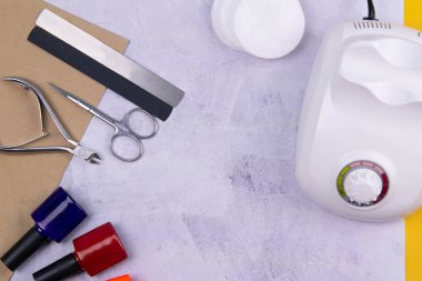 Set of cosmetic tools for manicure and pedicure on a concrete background. Gel polishes, milling cutter, nail files, scissors and tongs.