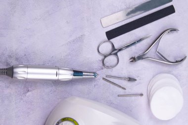 Set of cosmetic tools for manicure and pedicure on a concrete background. Gel polishes, milling cutter, nail files, scissors and tongs.
