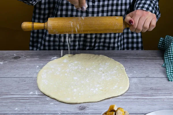 Eine Frau streut Mehl auf einen taufrischen Pizzateig — Stockfoto