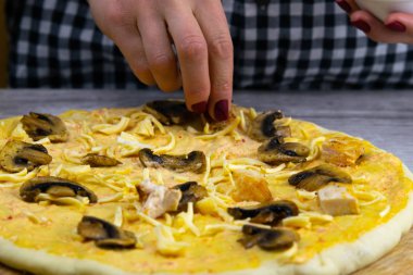 Kadın içmek için hamurun üzerine mantar serer. Taze İtalyan çiğ pizzası. Hazırlama süreci.