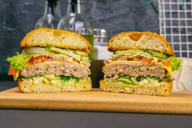 Kapalı hamburger ikiye bölünmüş, tahta bir tahtanın üzerinde duruyor, arka planda, ızgara....