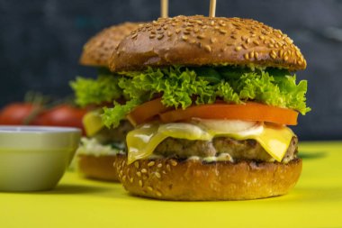 Patates kızartması, kıyma, sos ve biberin yanında duran iki yakın plan hamburger..