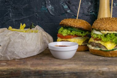 Patates kızartması, kıyma, sos ve biberin yanında duran iki yakın plan hamburger..