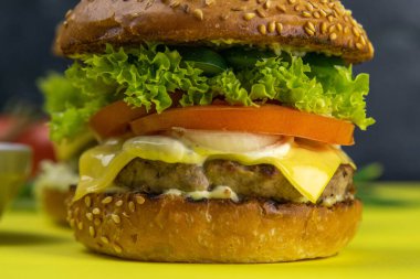 Patates kızartması, kıyma, sos ve biberin yanında duran iki yakın plan hamburger..