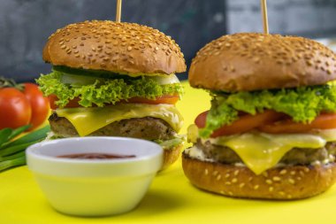 Patates kızartması, kıyma, sos ve biberin yanında duran iki yakın plan hamburger..