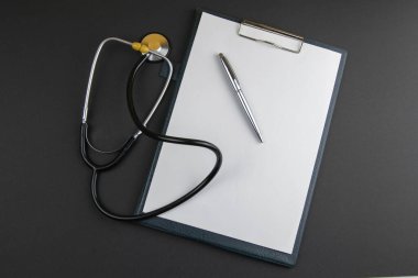 Gümüş kalemli beyaz kağıt, siyah arkaplanda fonendoskop ve metin için kopyalama alanı. İlaç kutsallığı.