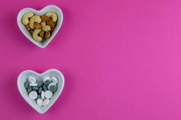 Concetto Salute Noci Contro Pillole Stanno Insalatiere Uno Sfondo Rosa — Foto Stock