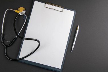 Gümüş kalemli beyaz kağıt, siyah arkaplanda fonendoskop ve metin için kopyalama alanı. İlaç kutsallığı.