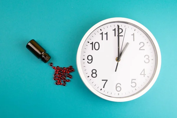 The concept of taking medication. Red pills and a clock that indicate the time of admission.
