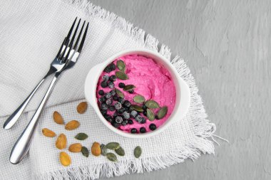 Reçelli süzme peynir, taze yaban mersini ve kabak tohumları seramik kasede, yakın plan. Lezzetli ve sağlıklı kahvaltı..