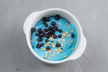 Reçelli süzme peynir, gri arka planda izole edilmiş seramik kasede taze yaban mersini ve kabağı tohumları. Lezzetli ve sağlıklı kahvaltı..