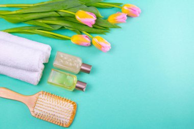 Yeşil masadaki spa tedavileri bir filiz, üç beyaz havlu, yağlar, avokadolar ve lalelerdir. Sağlıklı bir vücudun bahar kavramı.