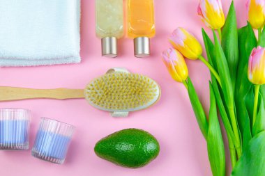 Üç havlu, vücut bakım yağı, avokado ve arka planda bir lale duruyor. Spa tedavisi kavramı, sağlıklı bir vücut..