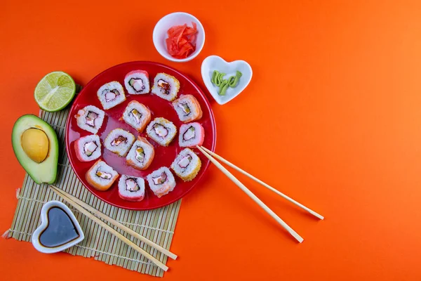 Piros Tányér Sushi Val Különböző Tekercsekkel Töltve Mellette Pálcikák Sushi — Stock Fotó
