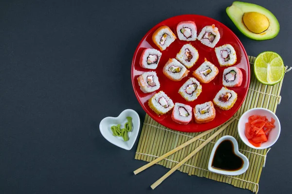 Piros Tányér Sushi Val Különböző Tekercsekkel Töltve Mellette Pálcikák Sushi — Stock Fotó