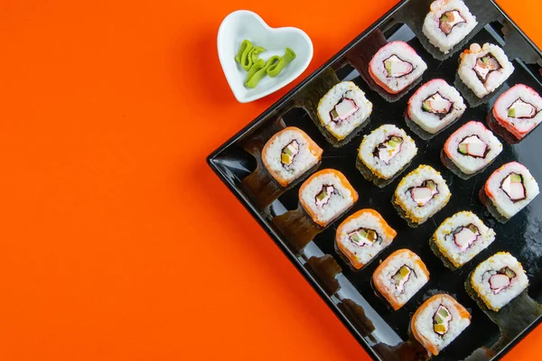 Czarna Płyta Sushi Wypełniona Rolkami Różnego Rodzaju Obok Stojaków Sushi — Zdjęcie stockowe