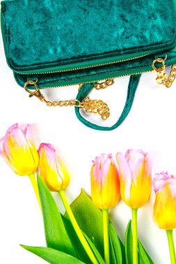 Beyaz arka planda yeşil kadın debriyajı ve kadın kozmetiği olan laleler..