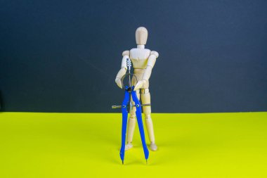 Sarı masasında pusula olan tahta adam figürü..