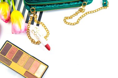 Yeşil kadın debriyajlı laleler, gölgeli paletler ve beyaz arka planda kadın kozmetikleri..