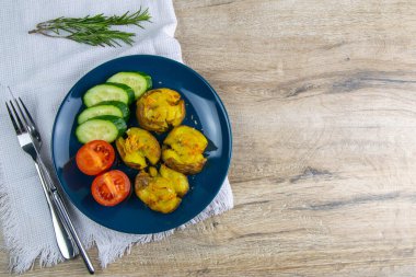 Peynirli fırında patates, domatesli salata ve mavi tabakta salatalık..