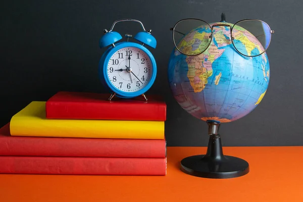 Een Stapel Boeken Klok Wereldbol Vrouwenbril Voorgrond Staan Een Oranje — Stockfoto