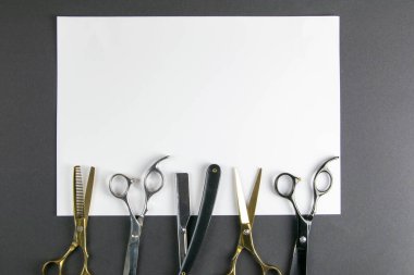 Makas, saç makası, tarak, siyah arka planda beyaz bir çarşaf üzerinde tehlikeli jilet. Kuaför konsepti.