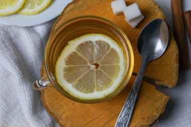 Naneli çayla şeffaf bardak tahta bir standın üzerinde, şeker küplü şeker kasesinin yanında, dilimlenmiş limon ve bir kaşık.