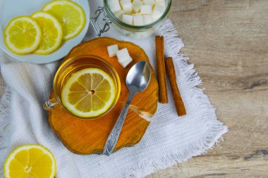 Naneli çayla şeffaf bardak tahta bir standın üzerinde, şeker küplü şeker kasesinin yanında, dilimlenmiş limon ve bir kaşık.