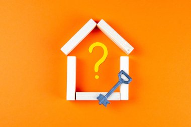 Ev, boyalı bir soru işaretinin içindeki ahşap parmaklıklardan yapılmış ve yanında anahtar duruyor..