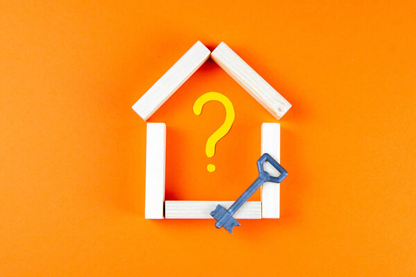 Дом сделан из деревянных брусков внутри расписного вопросительного знака, а рядом стоит ключ
.