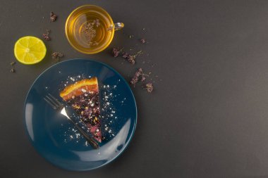 Mavi bir tabakta naneli ve limonlu nane yaprağı ve aynalı böğürtlenli yabanmersinli kek dilimleri siyah masanın üzerinde, yakın çekim. Üst Görünüm.