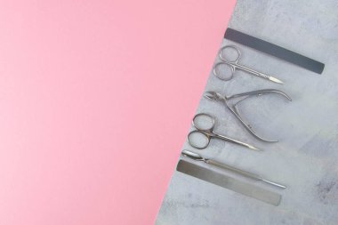 Manikür ve pedikür için kozmetik aletler. Manikür makası, tırnak eti, testere, değirmenci beton pembe arka planda duruyor. Açık alanlı en üstteki görünüm.