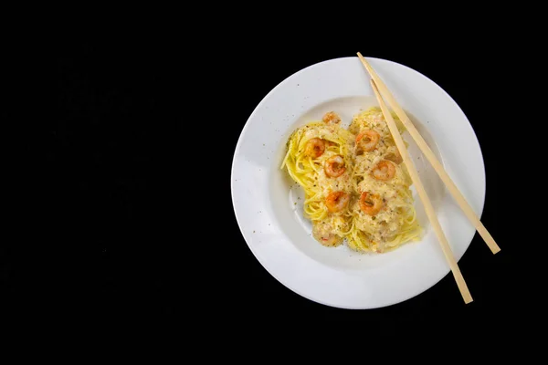 白皿のスパゲティエビ 黒の背景に隔離された魚介類と辛いトップビューの麺 クリッピングパス トップビュー — ストック写真