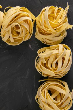 Çiğ tagliatelle makarna, siyah arka planda izole edilmiş..