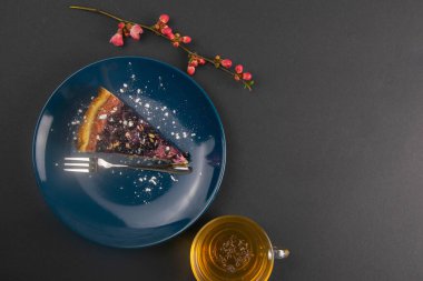 Mavi bir tabakta naneli ve limonlu nane yaprağı ve aynalı böğürtlenli yabanmersinli kek dilimleri siyah masanın üzerinde, yakın çekim. Üst Görünüm.