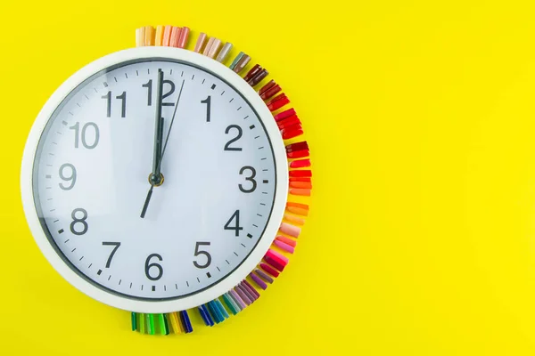 A set of cosmetic tools for manicure and pedicure on a blue background. The watch and palette of colors for manicureons on tips stands under the clock all standing on a yellow background.