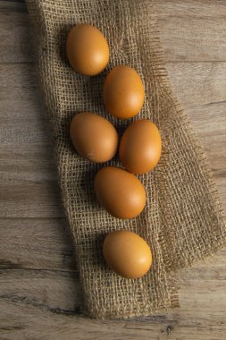 Yumurtalar kahverengi ahşap bir masada duran çuval bezi üzerinde durur..