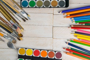 Sanatçı aksesuar koleksiyonu. Çadır bezi, bir tüp yağ boyası, sanat fırçaları, ahşap masada duran palet bıçağı. Sanatçı atölyesi arka planı.