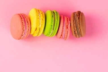 Renkli kurabiyeler pembe arka planda dururlar. Açık alanlı en üstteki görünüm