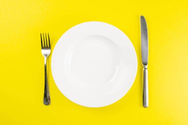 Bıçak ve çatal beyaz tabakta. Yaratıcı gıda konsepti. Üst görünüm, açık alanla yakın plan.